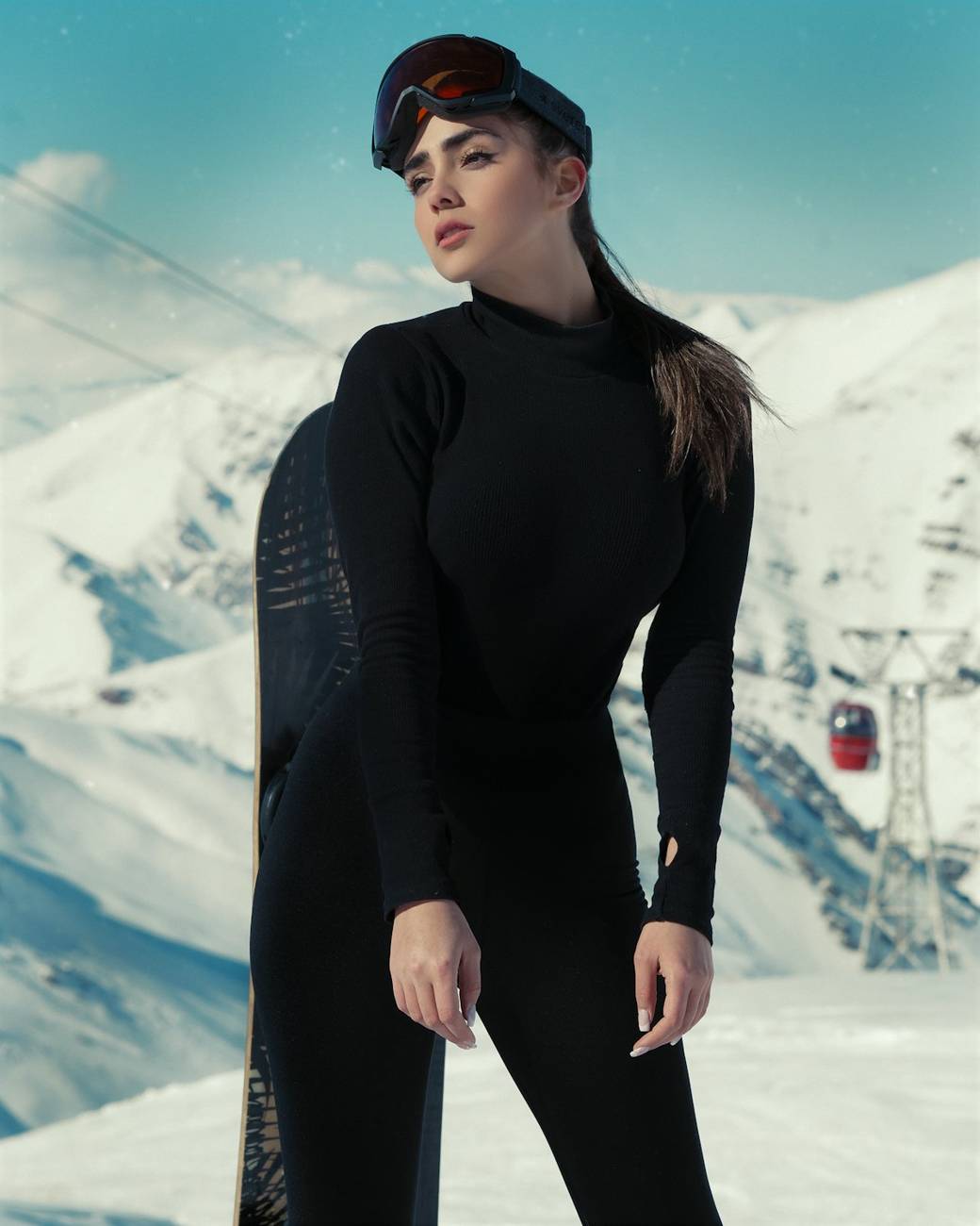 Model in all black standing against a snow face