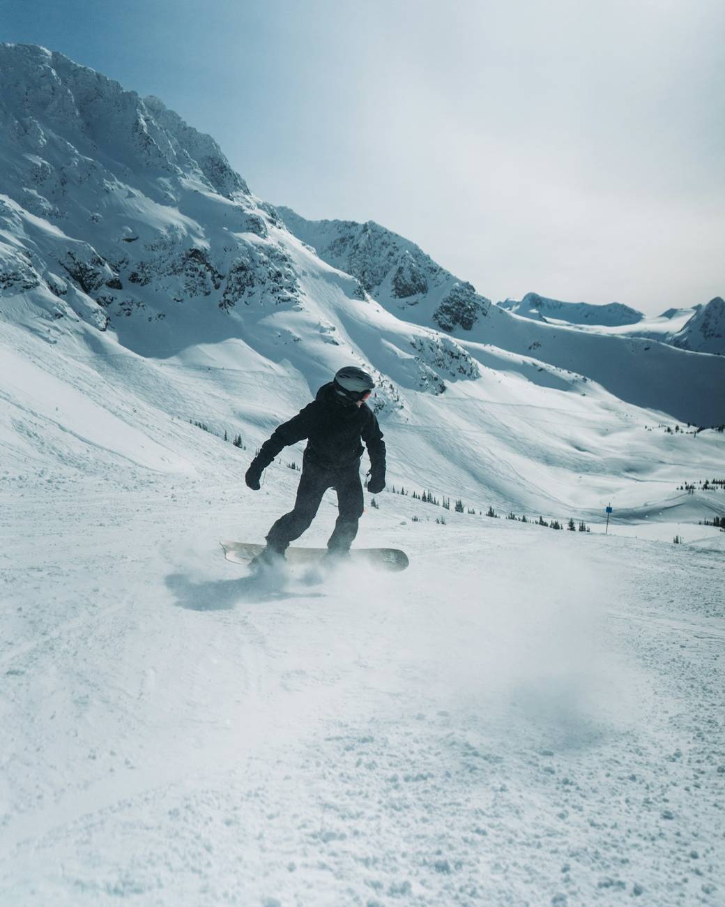 Snowboarder carving through open powder beneath a cloud bank