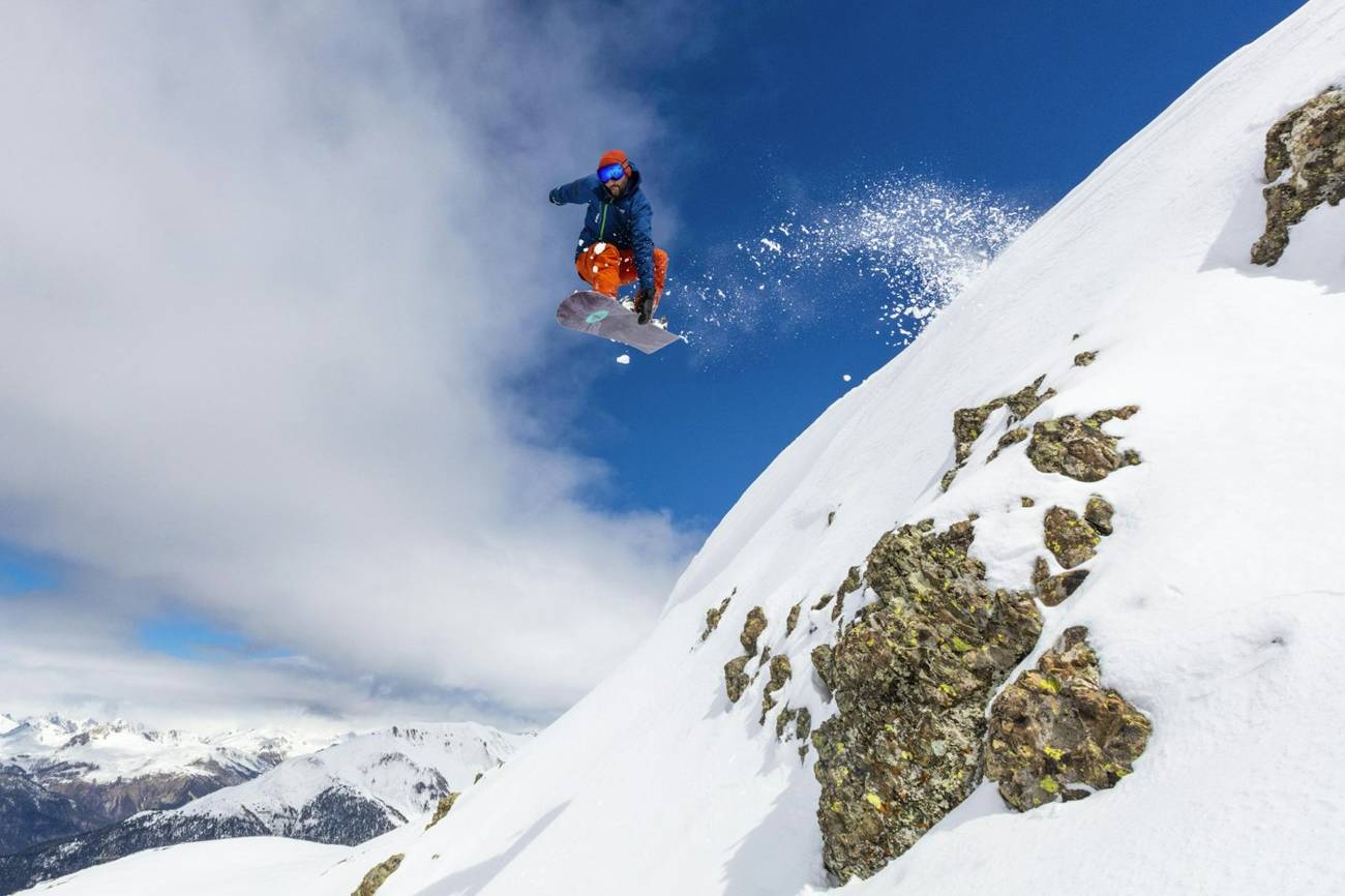 Snowboarder mid-air above a mountain face