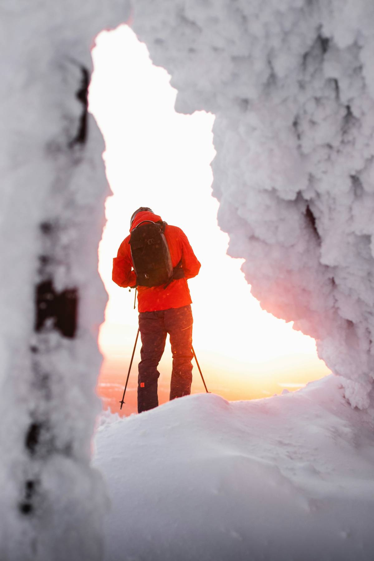 Skier framed by a rime-ice arch at sunrise
